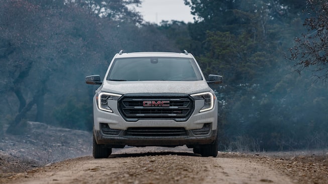 Summit White GMC Terrain AT4 Driving Head-On Off-Road in Snow in a Forest