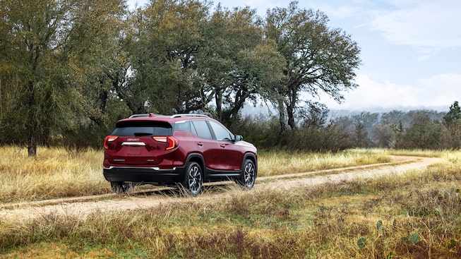 Red GMC Terrain SLT Driving Off-Road With Grass and Trees