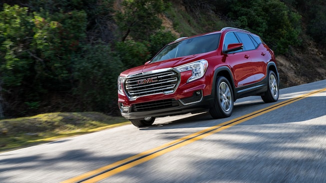 Red GMC Terrain SLT Driving On-Road With Trees and Hills