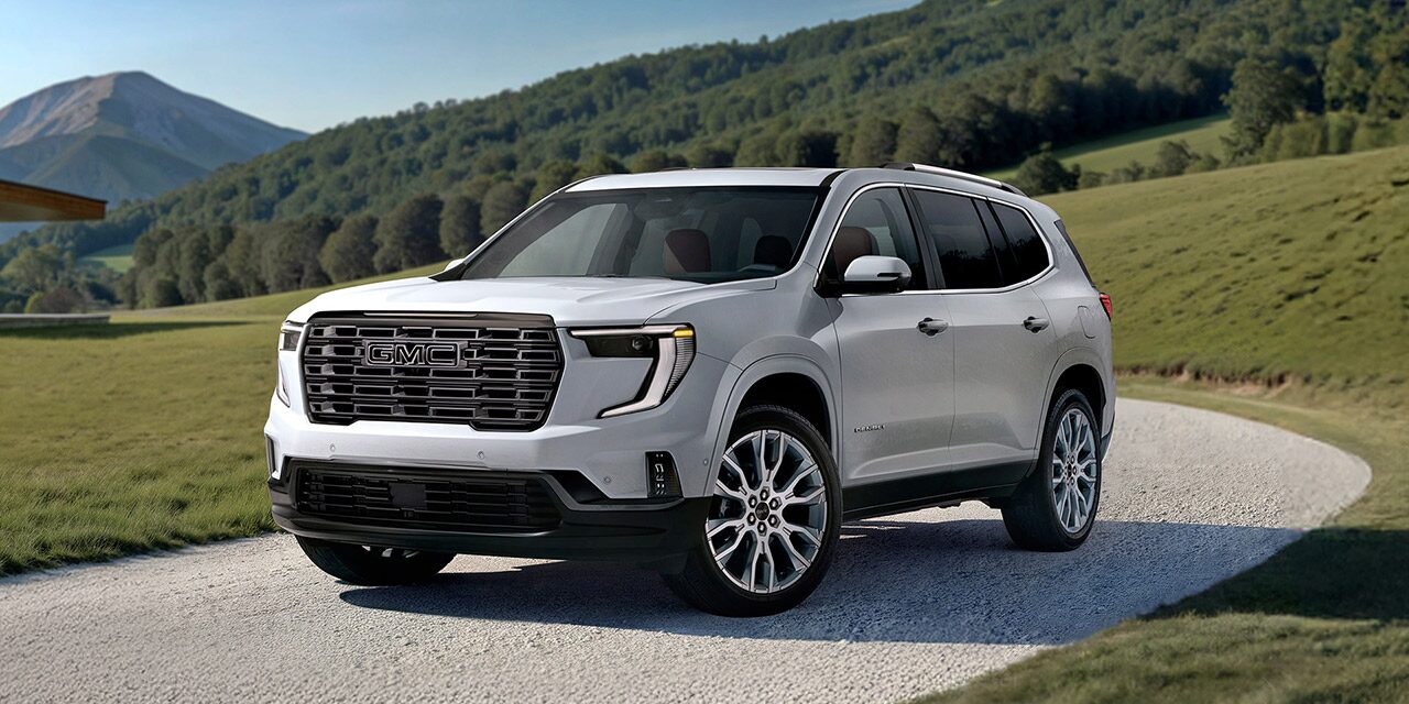 Front Three-Quarters View of the 2026 GMC Acadia Denali Ultimate Luxury Mid-Size SUV Driving Down a Long Driveway