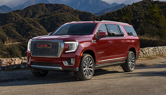 A Red GMC Yukon Denali SUV Parked on a Paved Road Overlooking a Mountain Range