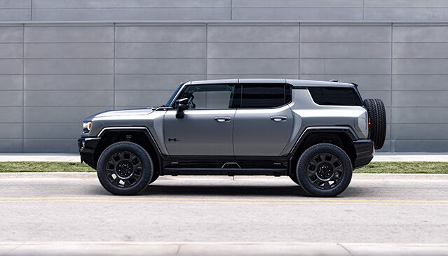 A Side View of a Gray GMC HUMMER EV SUV Parked Against a Modern Building Wall