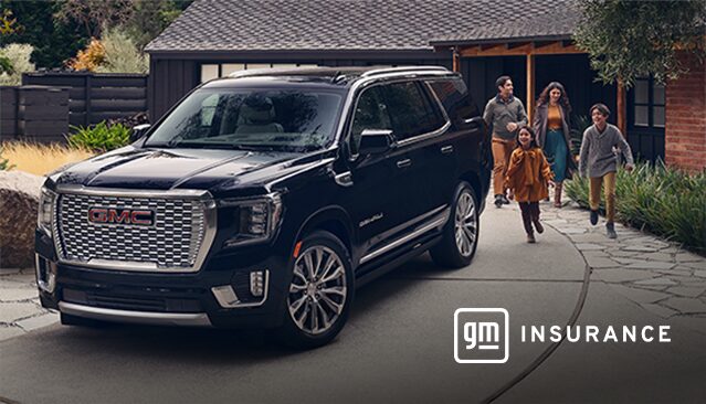 A Black GMC Yukon SUV Parked in a Driveway as a Family Walks Towards a Modern House with the GM Insurance Logo