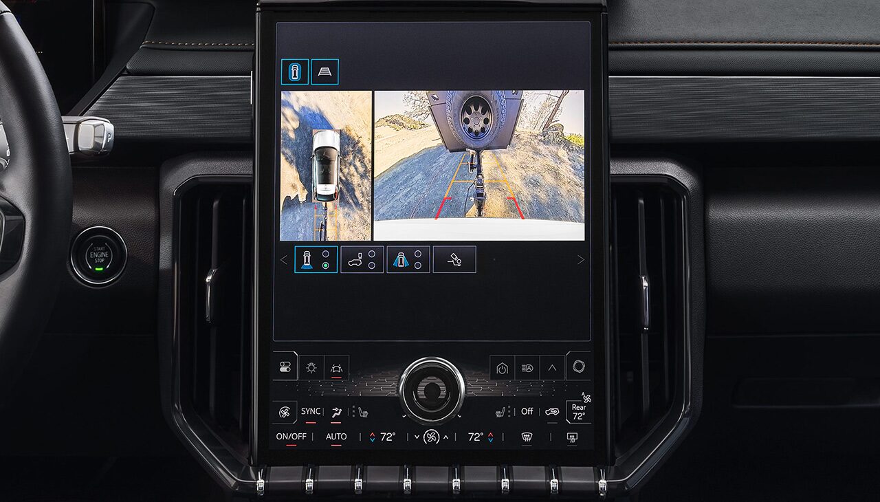 GMC Infotainment Screen Showing a Detailed Hitch View of a Trailer Hitch Being Connected to a Receiver on a Dirt Road