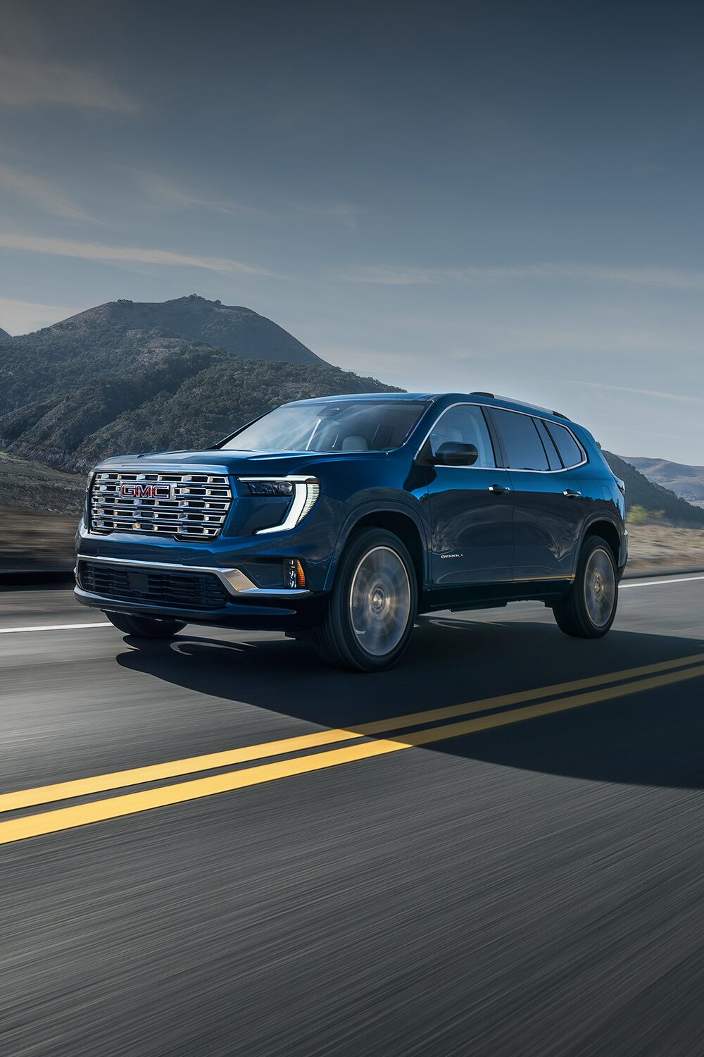 Dark Blue GMC Acadia SUV Driving Down a Scenic Mountain Road with a River in the Background