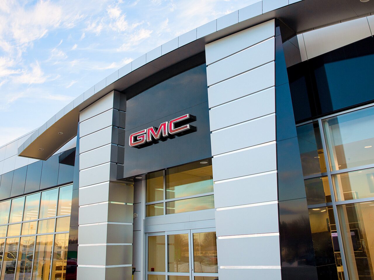 A GMC Logo on the Front of a Modern Dealership Building with Glass and Metal Accents