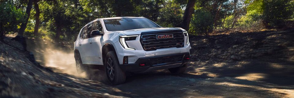 A GMC Acadia AT4 SUV Driving on a Dirt Path Through the Trees