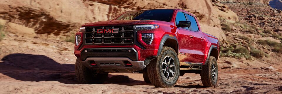 A GMC Canyon AT4 Truck Driving on a Dirt Path Next to Mountains