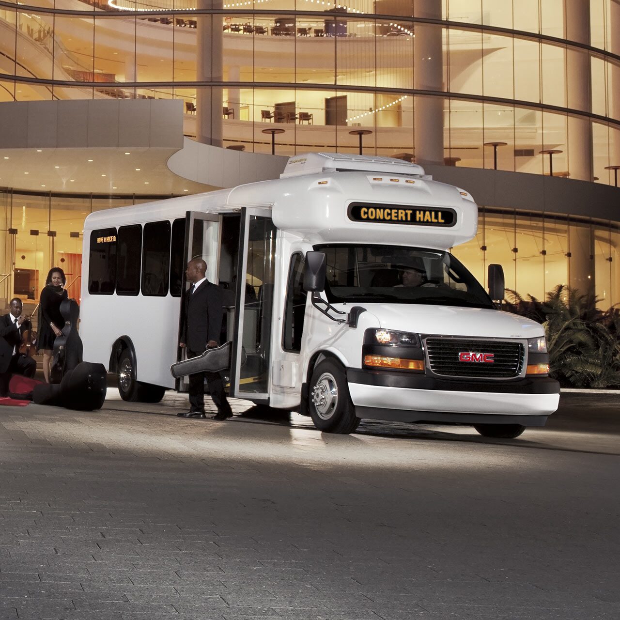 Front Three-Quarters View of the GMC Savana Cutaway Van Parked in Front of a Large Building