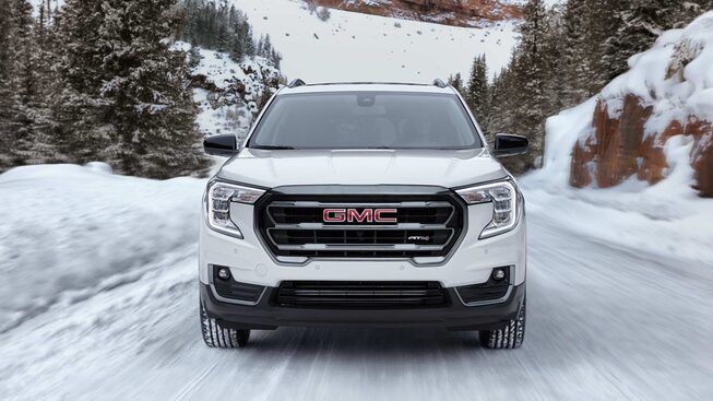 Summit White GMC Terrain AT4 Driving Head-On Off-Road in Snow in a Forest