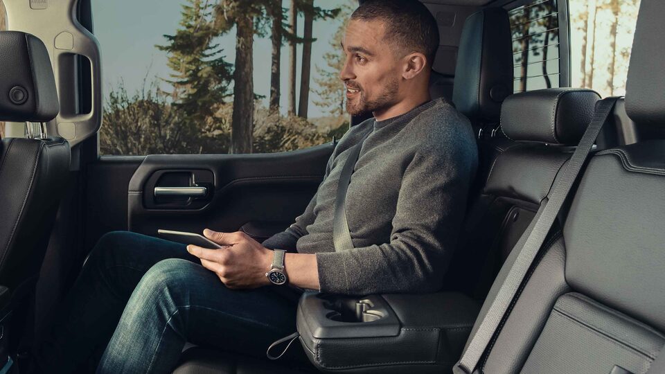 A Man Enjoys the Comfort of the Backseat of the Sierra HD while Driving Through the Woods