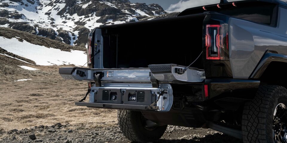 Rear End View of the 2025 Hummer EV Pickup Truck's MultiPro Tailgate Opened Overlooking Snowy Mountains