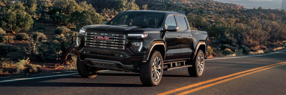 Three-quarter View of a 2025 GMC Canyon Denali Driving Down a Mountain Road