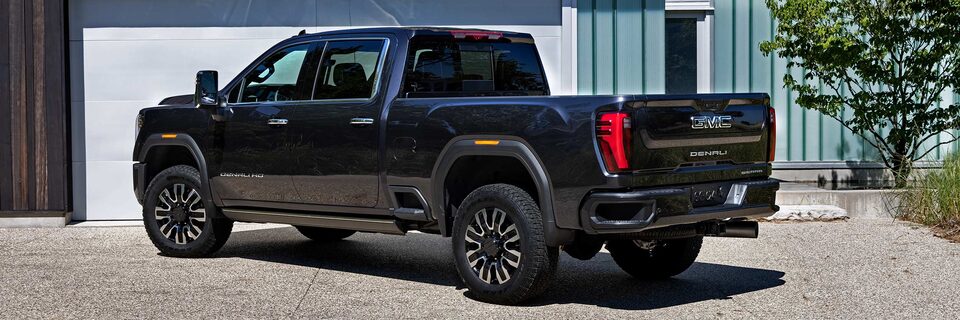 Wide Rear Three-Quarters View of a 2025 GMC Sierra HD Denali Truck Parked on Gravel