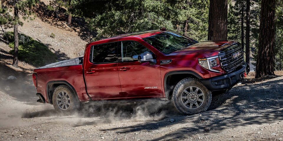 Red GMC Sierra 1500 Pickup Truck Driving Off-Road Through the Forest