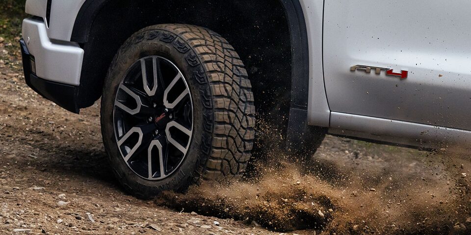 Close-up View of the Sierra AT4 Wheels and Rims Kicking up Dust on a Dirt Road