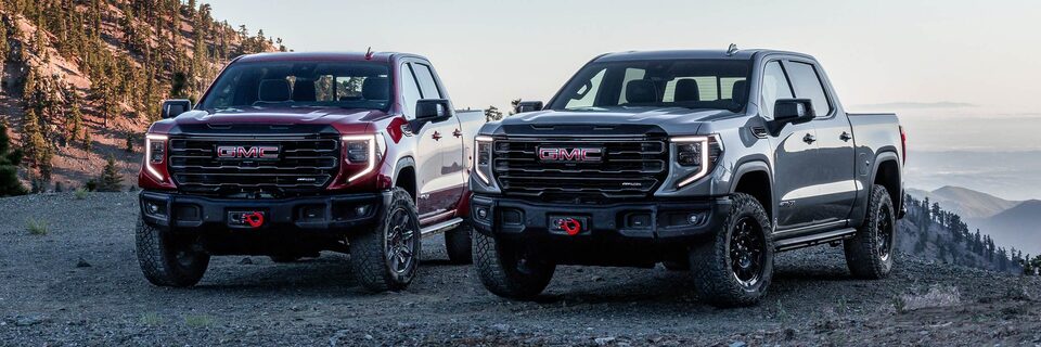 Front View of the GMC Sierra AT4 and the AT4X Next to Each Other with Mountains in the Distance