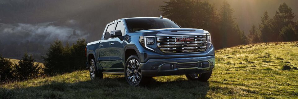 A Blue GMC Sierra 1500 Parked on a Hill as the Sun Shines Down on the Pickup Truck