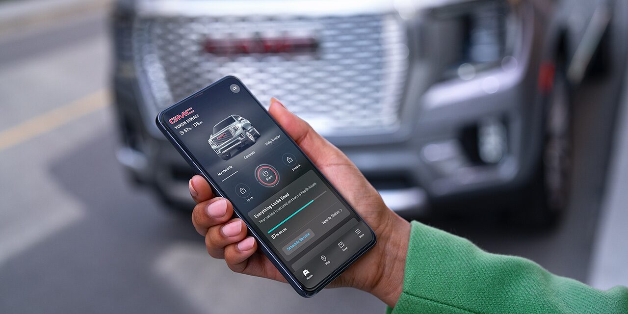 A Hand Holding a Smartphone Displaying the GMC Mobile App with Vehicle Status and Control Options