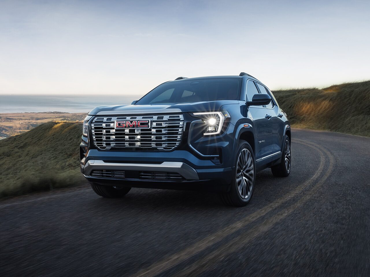Front Three-Quarters View of a 2026 GMC Terrain Denali Luxury SUV Driving Down the Coast