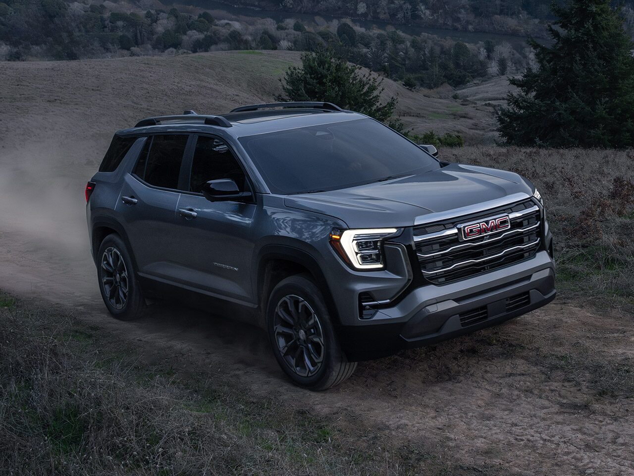 The 2026 GMC Terrain Elevation Compact SUV Driving up a Dirt Road at Dusk